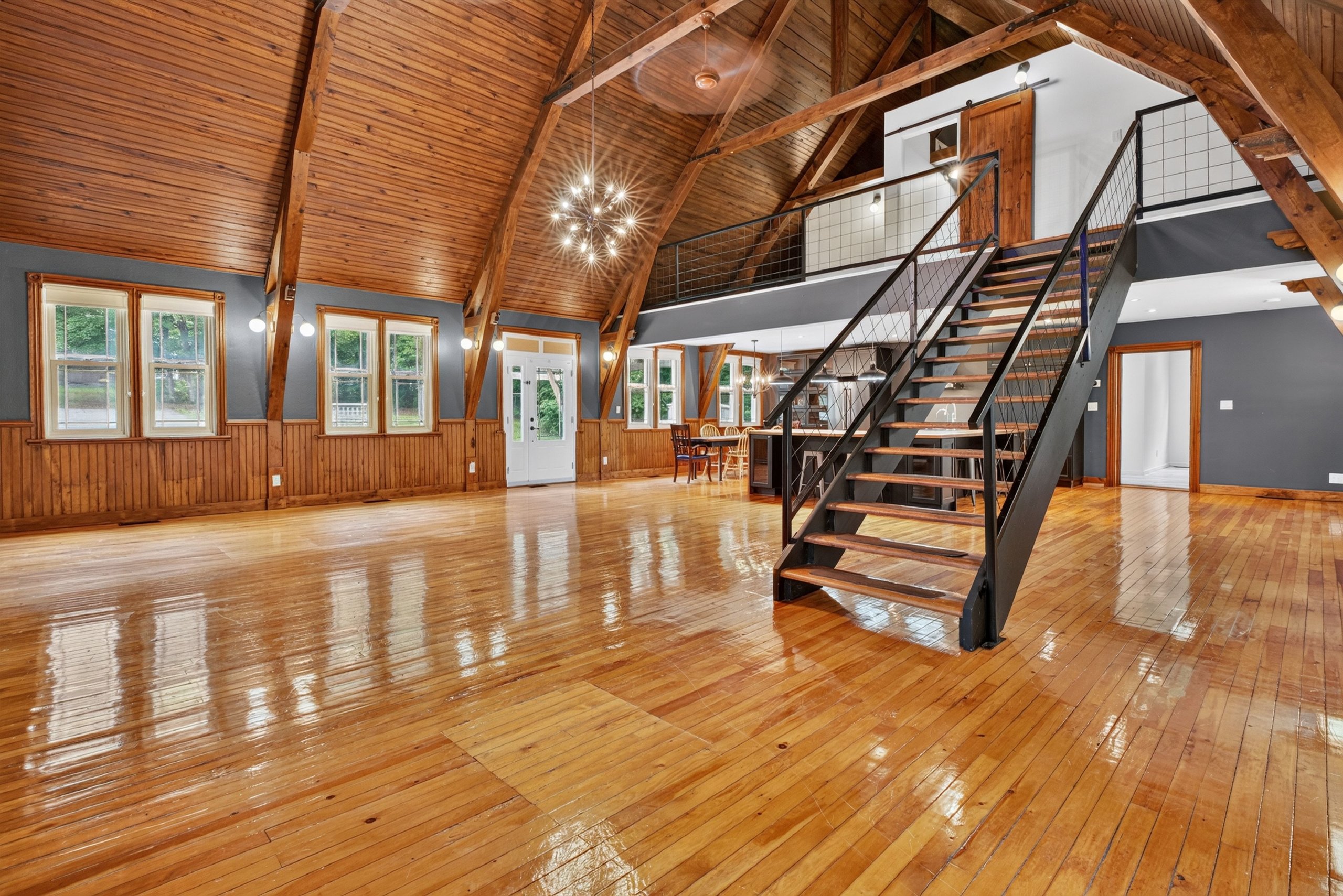 The great room of a converted 1902 church with soaring beamed ceilings and a floating staircase